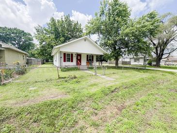 Charming single-story home with red accents, a cozy porch, and a partially fenced yard at 1002 S Fleming St, Indianapolis, IN 46241