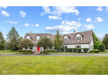 Sprawling two-story home featuring a red front door, mature trees, and a pristine lawn at 10594 Geist Rd, Fishers, IN 46037