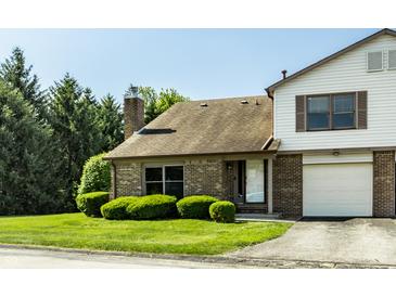 Charming brick townhouse featuring an attached garage, well-kept lawn, and mature trees at 2411 N Willow Way, Indianapolis, IN 46268