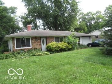Ranch-style home featuring a brick facade, large windows, and a well-maintained lawn surrounded by mature trees at 2610 Marywood Dr, Southport, IN 46227