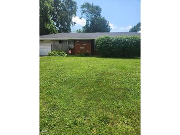 Traditional single-story home with a brick facade, green lawn, and mature landscaping at , Indianapolis, IN 46227