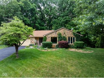 Charming stone-clad home with lush lawn, mature trees, and inviting landscaping creates a welcoming exterior at 3813 N Ramsgate Rd, Martinsville, IN 46151