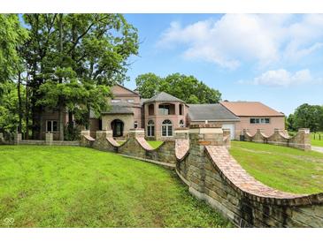 Stunning brick home featuring a curved brick retaining wall and beautiful landscaping at 7843 E Triple Crown Ln, Camby, IN 46113