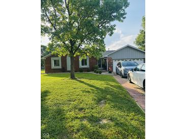 Charming brick ranch-style home featuring a lush green lawn and mature trees, offering great curb appeal at 1050 Laguna Ln, Greenwood, IN 46143