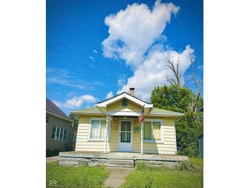 Charming bungalow featuring a front porch and a well-maintained lawn under a bright, cloudy sky at 130 S Arlington Ave, Indianapolis, IN 46219