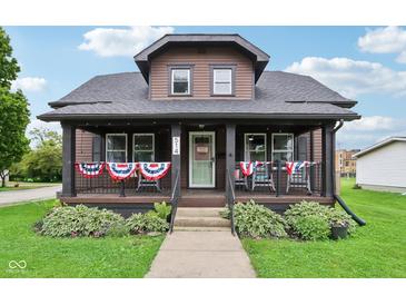 Charming two-story home with a covered front porch decorated with patriotic bunting and well-maintained landscaping at 514 E 2Nd St, Sheridan, IN 46069