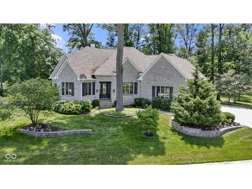 Charming stone home featuring manicured landscaping, a lush green lawn and mature trees at 10585 Golden Bear Way, Noblesville, IN 46060