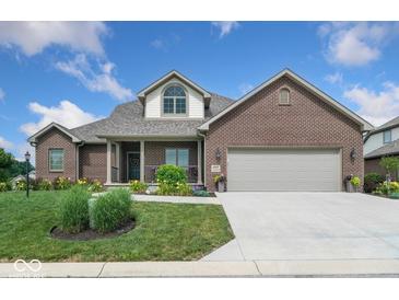 Charming brick home features a well-manicured lawn, attached two-car garage, and inviting covered front porch at 4909 N Graystone Dr, Muncie, IN 47304