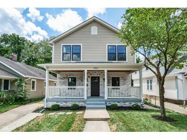 Charming two-story home with a covered front porch and a well-maintained lawn at 5930 Broadway St, Indianapolis, IN 46220