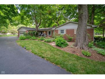 Charming brick home featuring mature trees and a well-manicured lawn and landscape at 7224 N Tuxedo St, Indianapolis, IN 46240