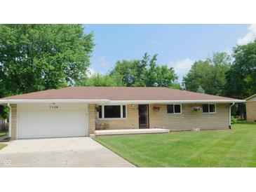 Charming single-story home featuring a stone facade, attached garage, and well-manicured lawn at 7326 Lowe Dr, Lawrence, IN 46226