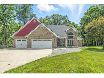 Charming brick home features a three-car garage and a well-maintained front yard with mature trees at 1066 N Dogwood Way, Greenfield, IN 46140