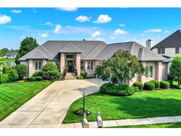 Stunning brick home featuring a grand entrance, manicured lawn, and a circular driveway on a sunny day at 14737 Macduff Dr, Noblesville, IN 46062