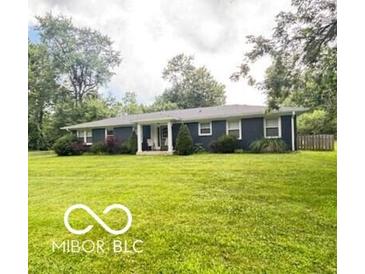 Charming single-story home with a well-manicured lawn and mature trees providing shade at 6546 Derbyshire Rd, Indianapolis, IN 46227