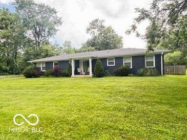 Ranch style home featuring a well-manicured lawn and cozy front porch at 6546 Derbyshire Rd, Indianapolis, IN 46227