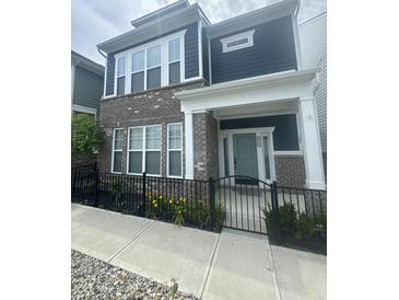 Charming two-story townhome with brick and vinyl siding, black iron fence, sidewalk and front yard at 9215 Hawley Dr, Indianapolis, IN 46216