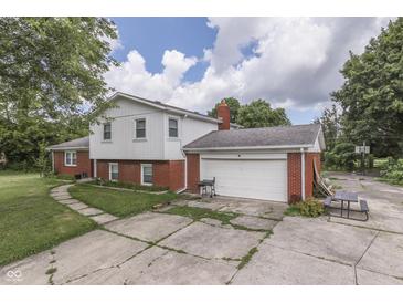 Two-story home featuring a brick garage, partial brick facade, and concrete driveway at 1924 W 65Th Pl, Indianapolis, IN 46260
