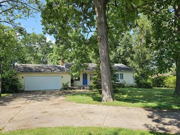 Charming home featuring an attached garage and welcoming blue front door surrounded by mature trees at 2024 E 41St St, Anderson, IN 46013