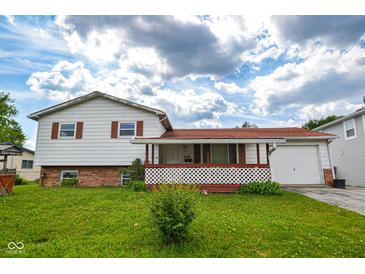 Charming two-story home with a red roof, white siding, covered front porch, and a lush front lawn on a sunny day at 2520 Tesh Dr, Indianapolis, IN 46203