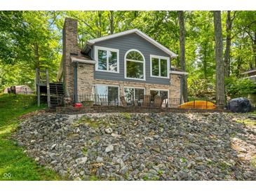 Charming brick home featuring a lakeside patio and serene views surrounded by lush trees at 6300 Grouse Dr, Nineveh, IN 46164