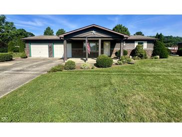 Charming single-story home with a covered porch, an American flag, and a beautifully landscaped front yard at 474 N Kristi Rd, Martinsville, IN 46151