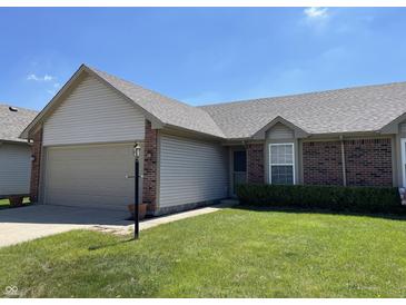 Charming home with a two-car garage, neat landscaping and green lawn on a sunny day at 7259 Registry Dr, Indianapolis, IN 46217