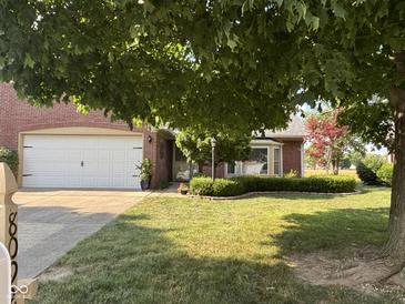 Charming brick home with a two-car garage and a well-manicured lawn, shaded by a mature tree at 8092 Crystal Ct, Avon, IN 46123