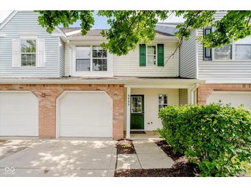 Charming townhome featuring an attached garage, green door, and well-maintained landscaping at 9689 Exchange St, Fishers, IN 46038