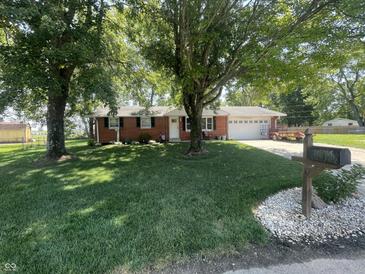 Charming brick ranch home with mature trees and a lush green lawn in a serene neighborhood at 9783 Lee Ct, Columbus, IN 47203