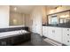 Modern bathroom features a soaking tub, walk-in shower, black tile accents, and a vanity with black countertops at 8722 Rockwood Ln, Indianapolis, IN 46259