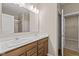 Bathroom featuring double sinks, light countertops, wooden cabinets, large mirror, and a shower behind glass at 2184 Galleone Way, Plainfield, IN 46168