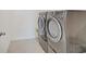 Modern laundry room featuring a gray, front-loading washer and dryer set and tile floor at 2898 Creekridge Ct, Columbus, IN 47201