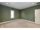 A simple bedroom with an olive green wall and beige carpeting, a window and a white door at 4499 W 131St St, Carmel, IN 46074