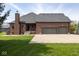 Brick house featuring a three-car garage with an expansive driveway and manicured lawn at 4499 W 131St St, Carmel, IN 46074