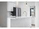 A pristine white kitchen features stainless steel appliances, pendant lights, and a view to the balcony at 806 7Th St, Columbus, IN 47201
