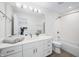 Bright bathroom featuring a large mirror, white cabinets, and modern fixtures; bathtub and shower combination at 822 7Th St, Columbus, IN 47201