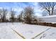 Snowy backyard features a chain-link fence, bare trees and a charming outbuilding with a white roof under a blue winter sky at 5845 Rawles Ave, Indianapolis, IN 46219