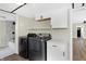 A spacious laundry room featuring modern washer and dryer, bright white cabinets, and a view of the bathroom at 5845 Rawles Ave, Indianapolis, IN 46219