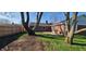 Large backyard with mature trees, a brick house and a patio with a grill at 3230 Meadowcrest Dr, Anderson, IN 46011