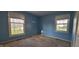 Empty bedroom with light blue walls, carpet, and two large windows offering outdoor views at 3230 Meadowcrest Dr, Anderson, IN 46011