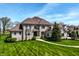 Beautiful two-story stone home featuring lush green lawn and mature trees under a bright, partly cloudy sky at 11492 Hanbury Manor Blvd, Noblesville, IN 46060