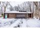 Snow covered driveway leads to a charming brown house with a two-car garage and blue door at 10555 E 400 S, Zionsville, IN 46077