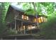 A rustic log cabin with a multi-level deck is set amongst lush greenery and features bright, inviting interior lighting at 6486 Coyote Dr, Nineveh, IN 46164