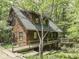Charming cabin-style home featuring wood siding, a deck, and surrounded by lush greenery and mature trees at 6486 Coyote Dr, Nineveh, IN 46164