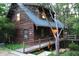 A charming wood cabin features a wooden walkway and staircase, enhanced by the surrounding lush forest at 6486 Coyote Dr, Nineveh, IN 46164