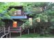 A rustic cabin, surrounded by lush greenery, showcasing an inviting deck and cozy, warm interior lighting at 6486 Coyote Dr, Nineveh, IN 46164