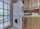 A stackable washer and dryer are nestled beside wooden cabinets, offering a practical and organized laundry space at 6486 Coyote Dr, Nineveh, IN 46164