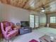A pink armchair sits in the living room, which is adorned with wooden ceilings and a patterned accent wall at 6486 Coyote Dr, Nineveh, IN 46164