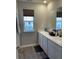Bathroom featuring a window, double sink vanity, and laminate floors at 7108 Parkstay Ct, Indianapolis, IN 46113