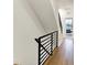 Bright hallway with hardwood floors and a modern railing leading to an open door at 527 E North St, Indianapolis, IN 46204
